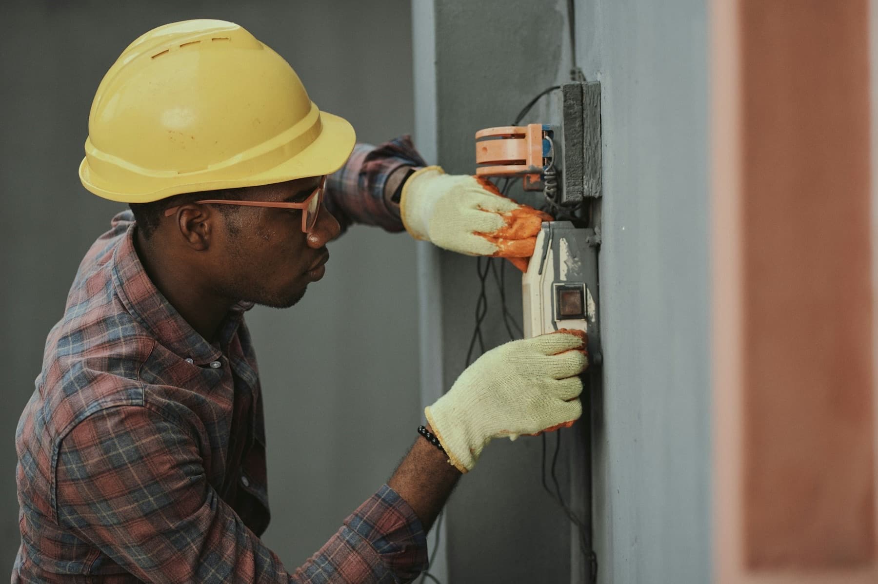 An electrician wiring a panel with both hands occupied