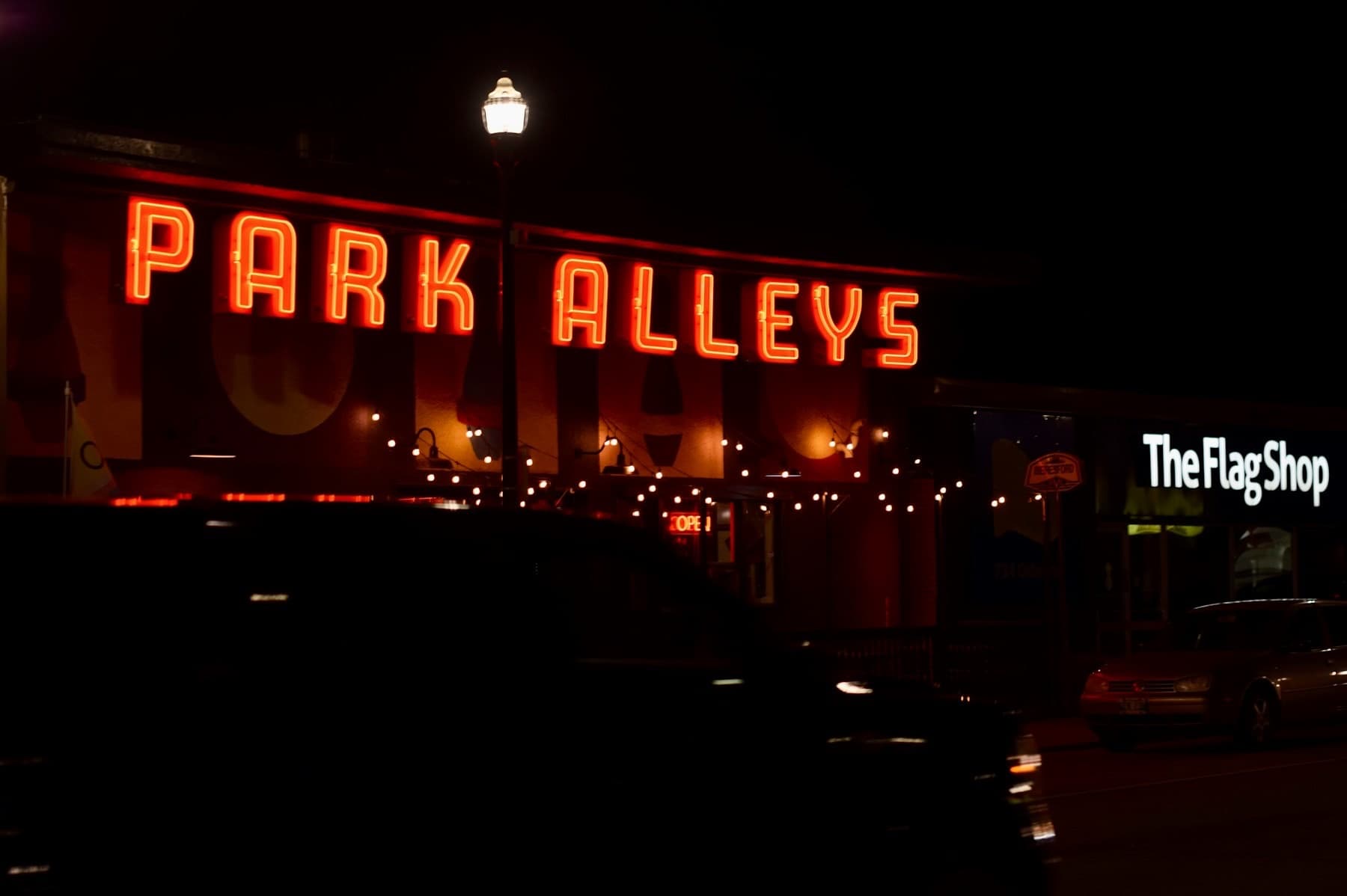 A business name in red neon lettering above a shopfront at night