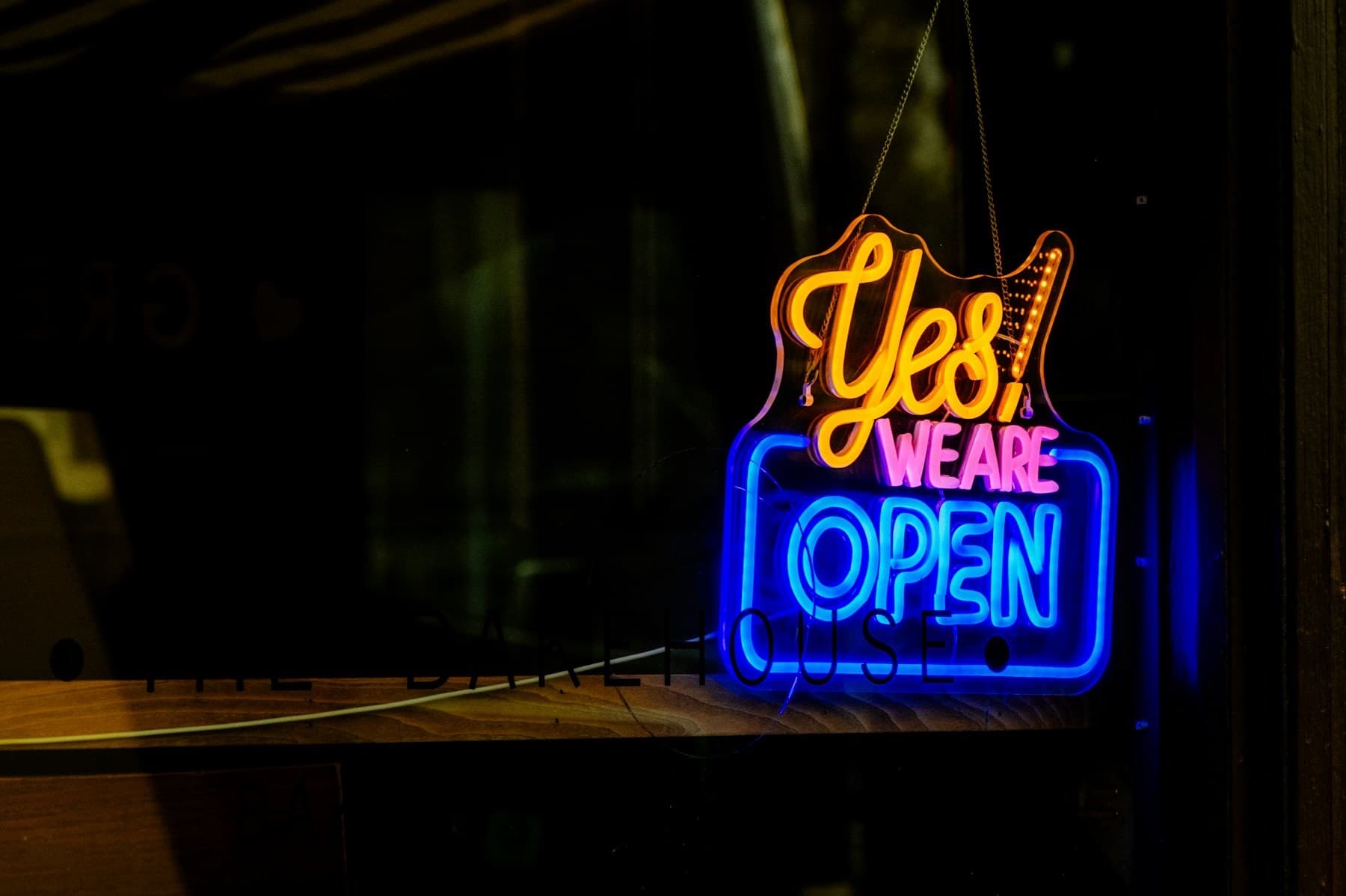 Neon sign in a shop window reading Yes, we are open