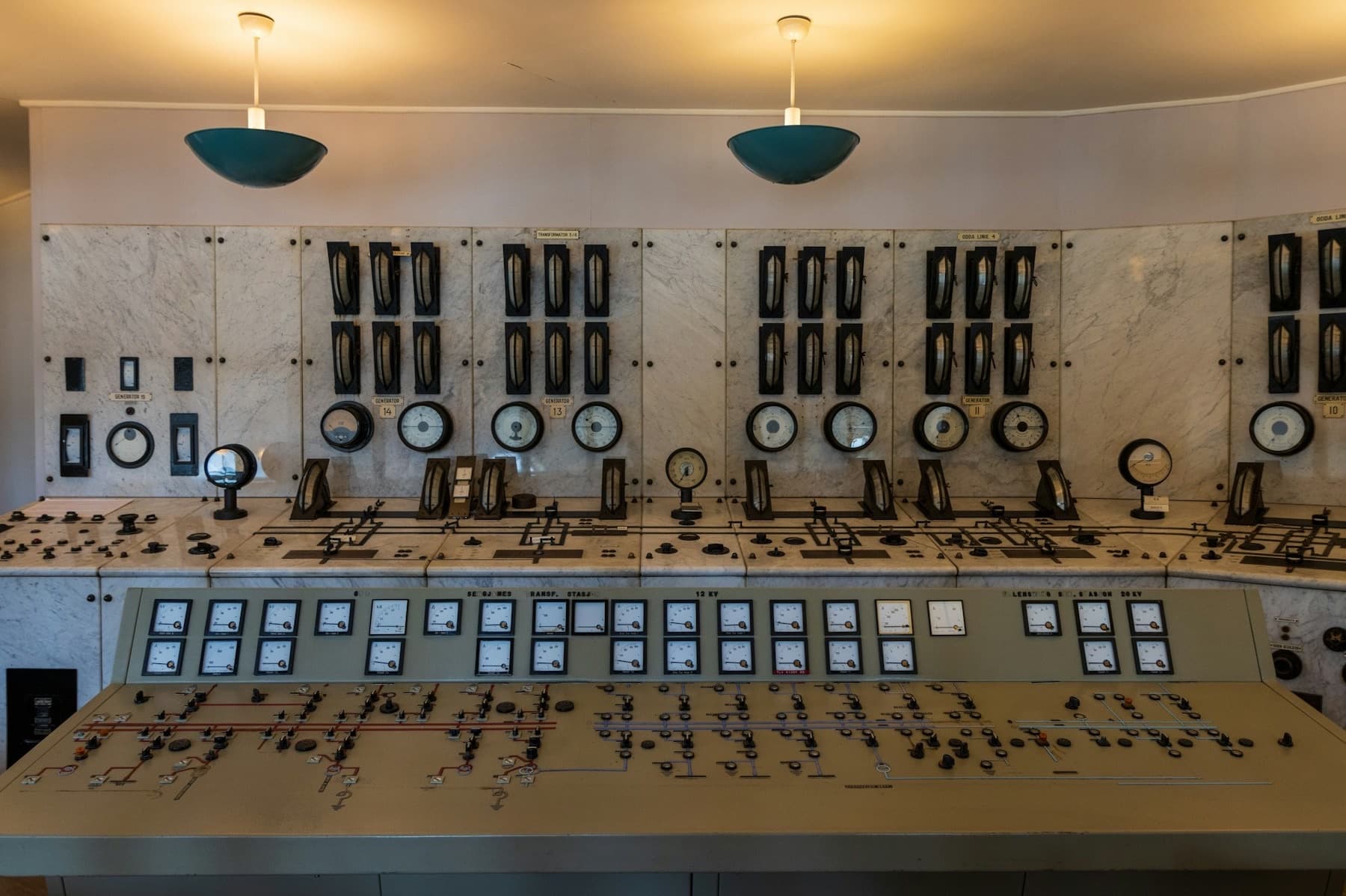 An old control room lined with dials, gauges and switches, with no operator present