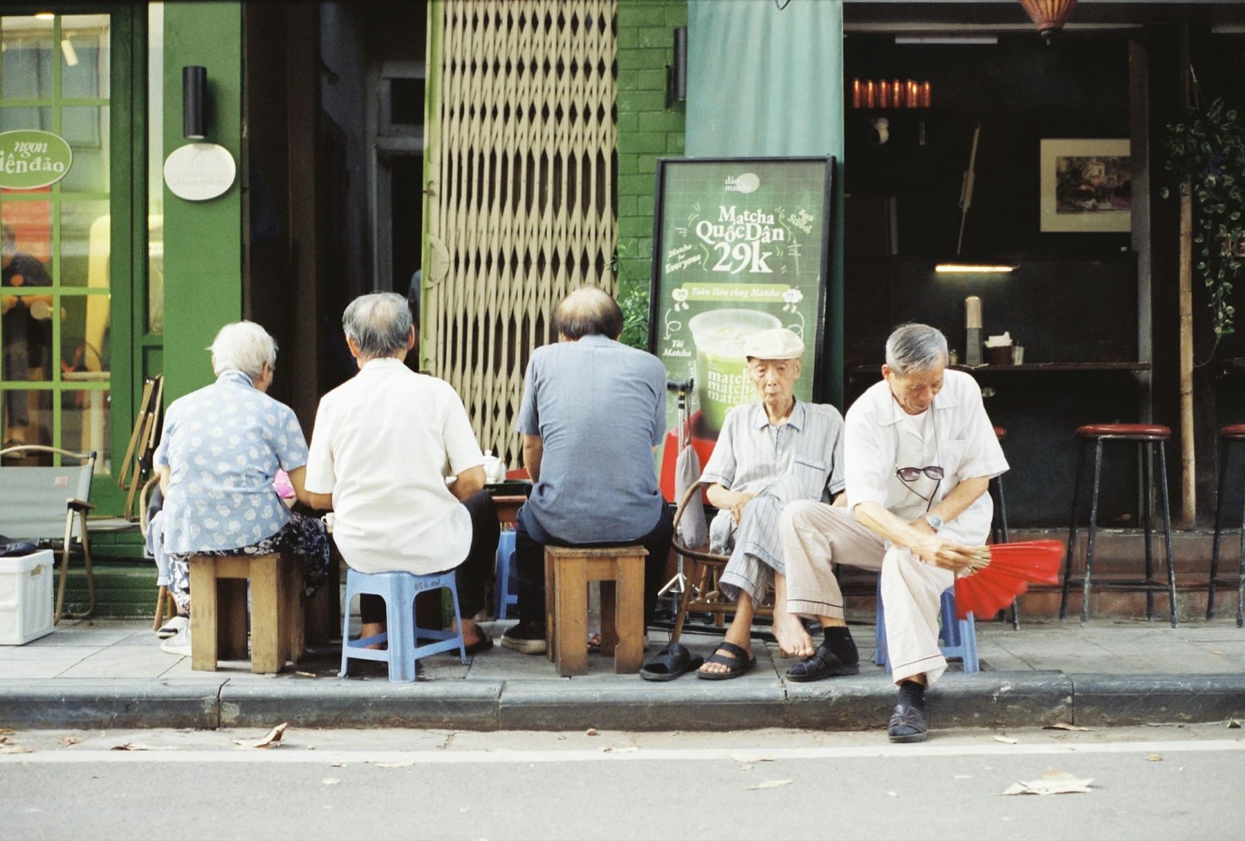 Neighbours sitting on stools outside a local shop, talking